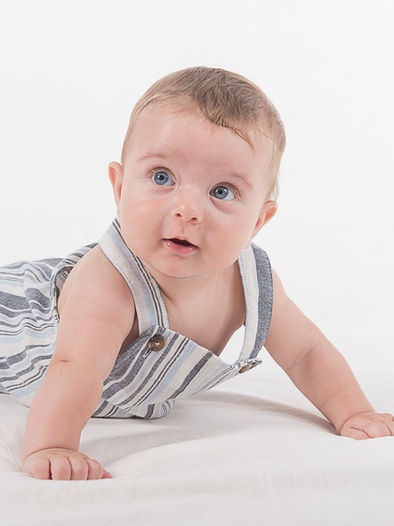 Bebé caucasiano de 9 meses com cabelo loiro e olhos azuis, sorridente e expressivo, sentado e brincando. Mostra alegria e ternura, transmitindo autenticidade e encanto infantil.