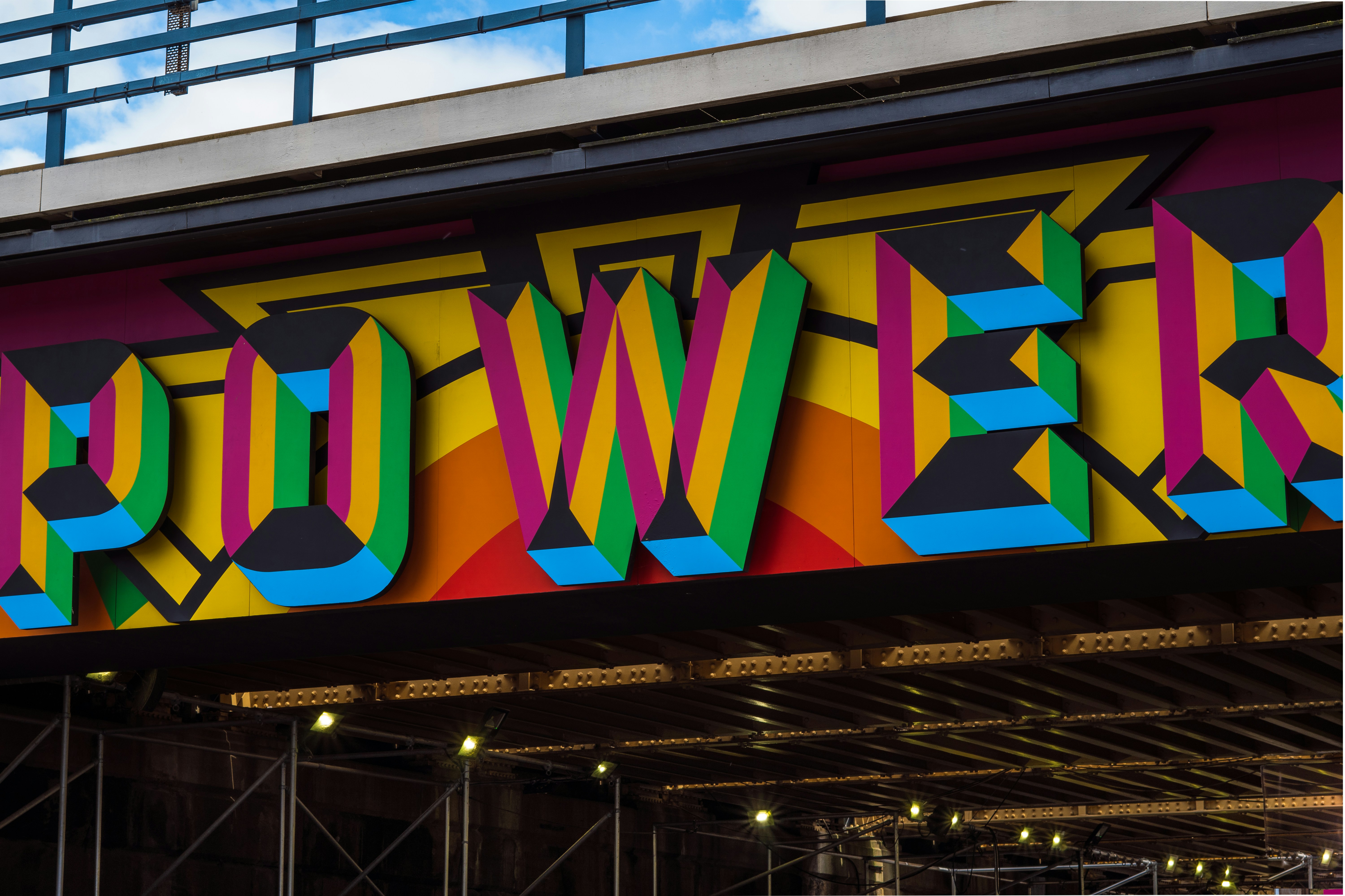 Colourful sign on top of an underpass that says Power