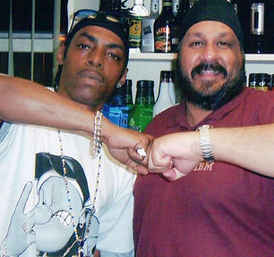 A black man stands next to a Sikh man. They're fist bumping.