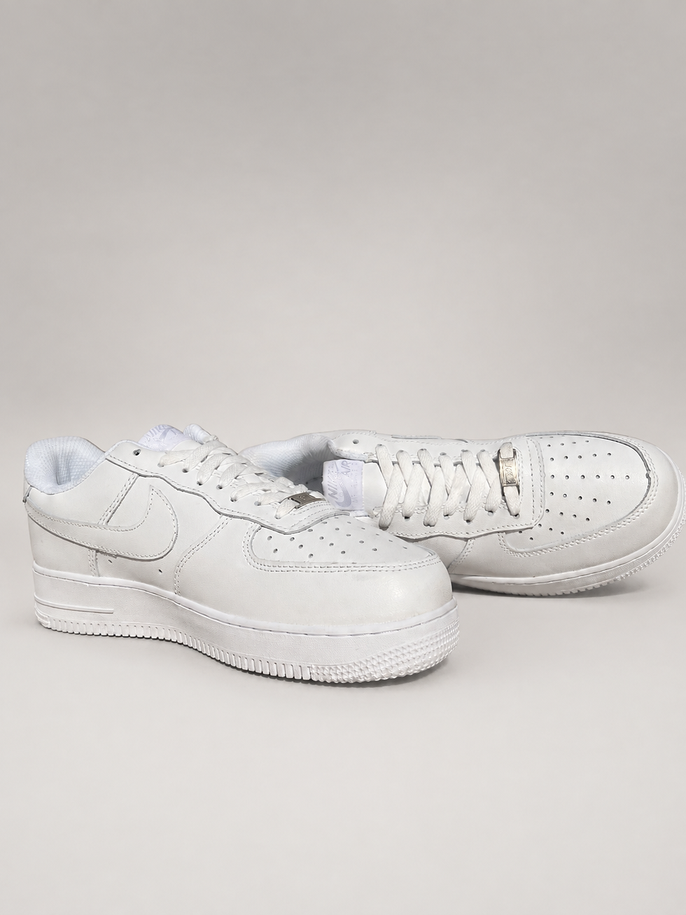 Thumbnail: Pair of Nike Air Force 1 '07 white leather sneakers angled front and side view