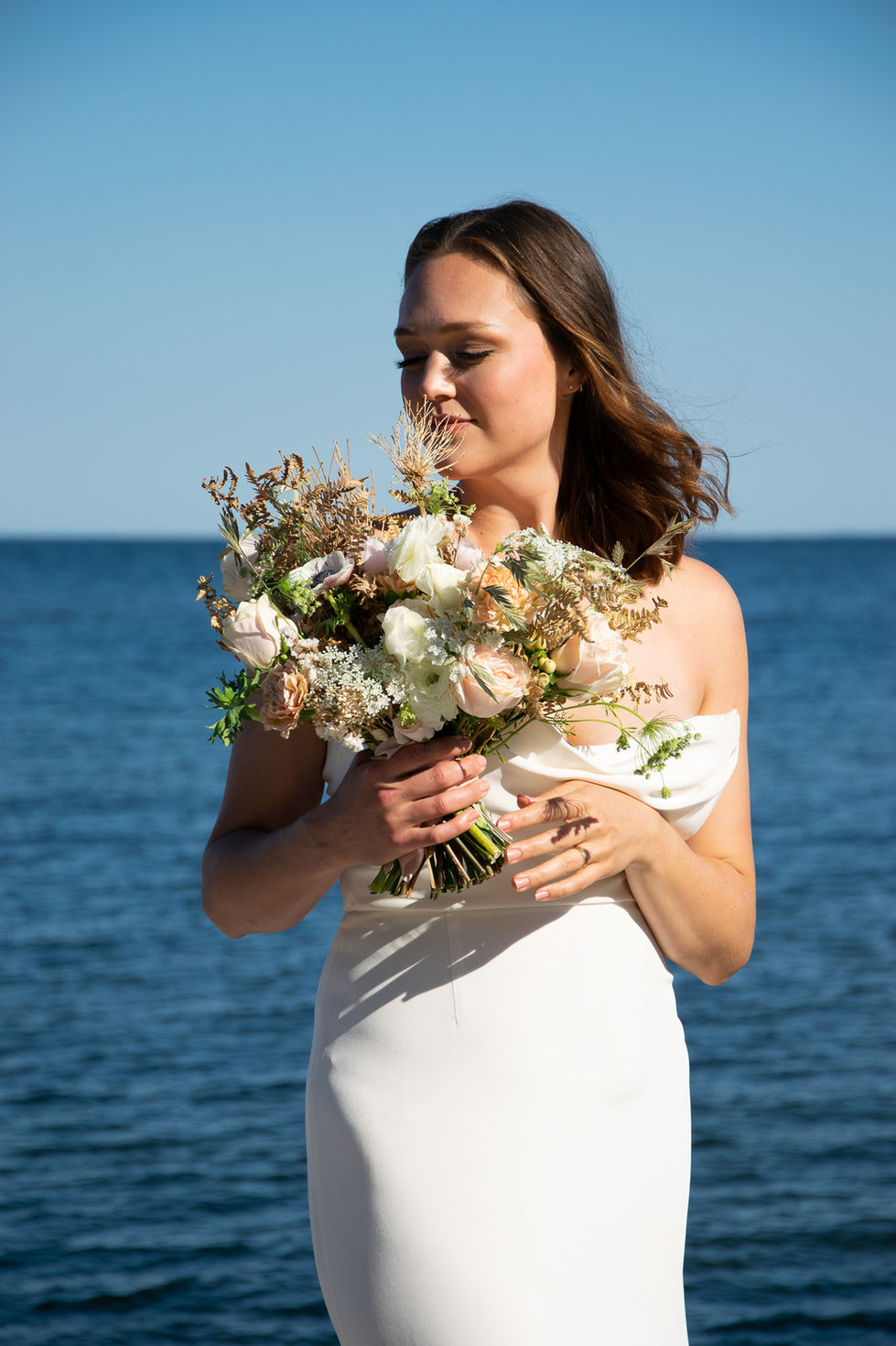 bride in front of lake holding her bouquet while the sun illuminates the scene — wedding photography by Shutter & Sojourn