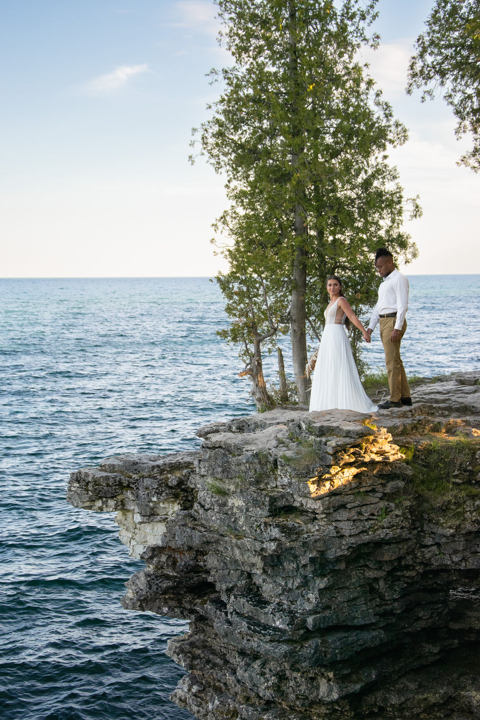 bride leading groom to edge of cliff overlooking Lake Michigan — wedding photography by Shutter & Sojourn