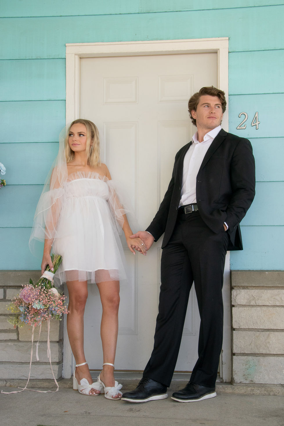 elopement bride and groom standing in front of motel door looking opposite directions and holding hands — wedding photography by Shutter & Sojourn