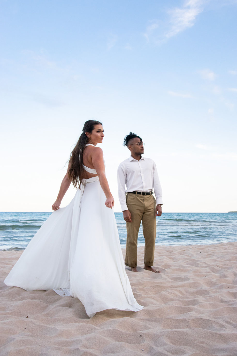 editorial portrait of bride and groom on the beach at sunset looking off into different directions — wedding photography by Shutter & Sojourn