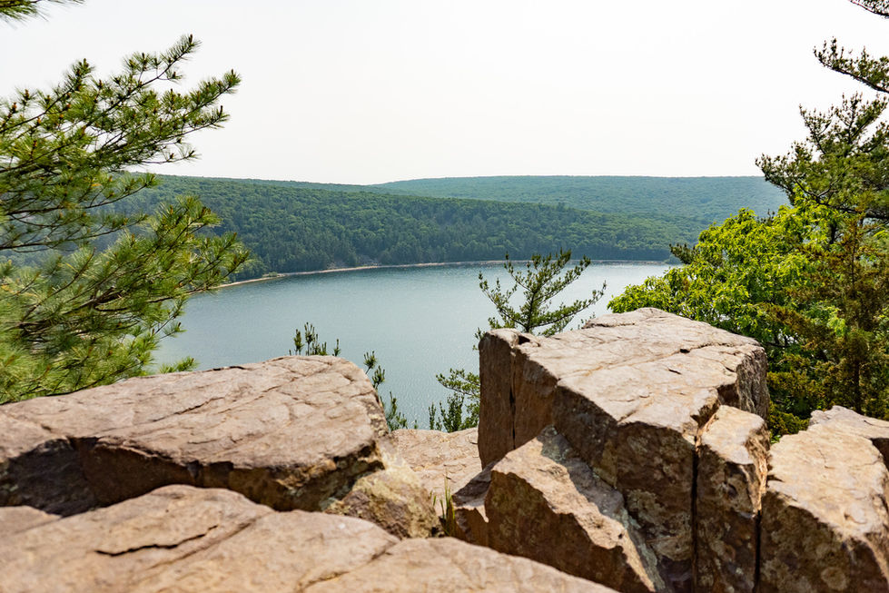 Boulders at the edge of a cliff with forest and lake — travel photography by Shutter & Sojourn