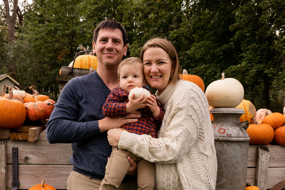 family photo with toddler holding white pumpkin surrounded by pumpkins on a wagon — family photography by Shutter & Sojourn