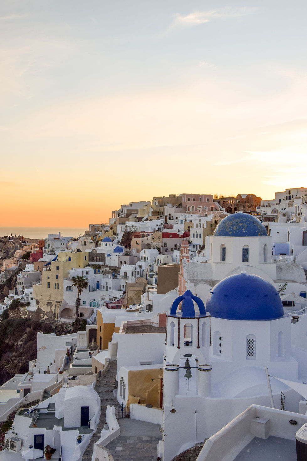 Santorini sunset in Oia with blue domed churches and orange skies — travel photography by Shutter & Sojourn