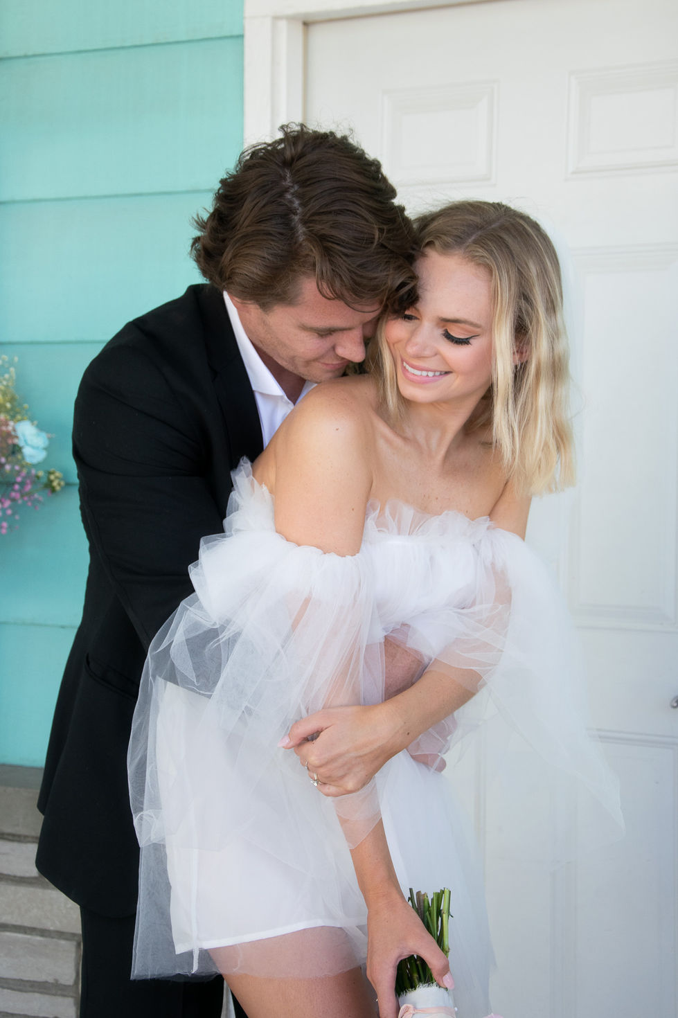 groom hugging bride from behind while she looks back at him and smiles — wedding photography by Shutter & Sojourn