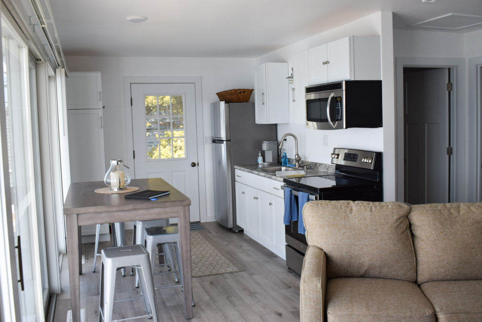 small shot gun kitchenette with high top table and grey stools — real estate photography by Shutter & Sojourn