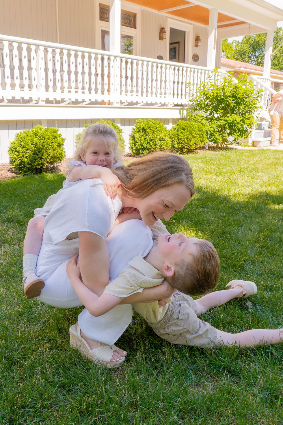 two small kids laughing as they try to tackle their mother