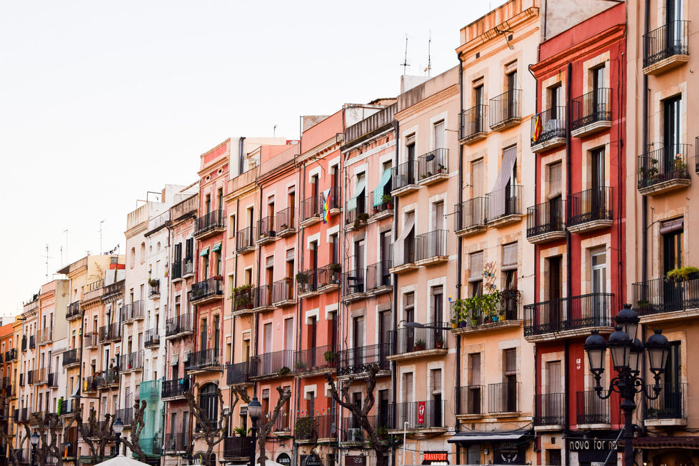 brightly colored pink, red, and orange buildings with black iron balconies in tarragona, Spain — travel photography by Shutter & Sojourn