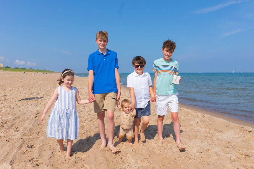 cousins and grandchildren holding hands walking down a sandy beach in Michigan