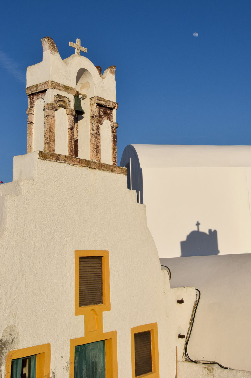 white stucco church with yellow framed windows and green door and the moon in the blue sky — travel photography by Shutter & Sojourn