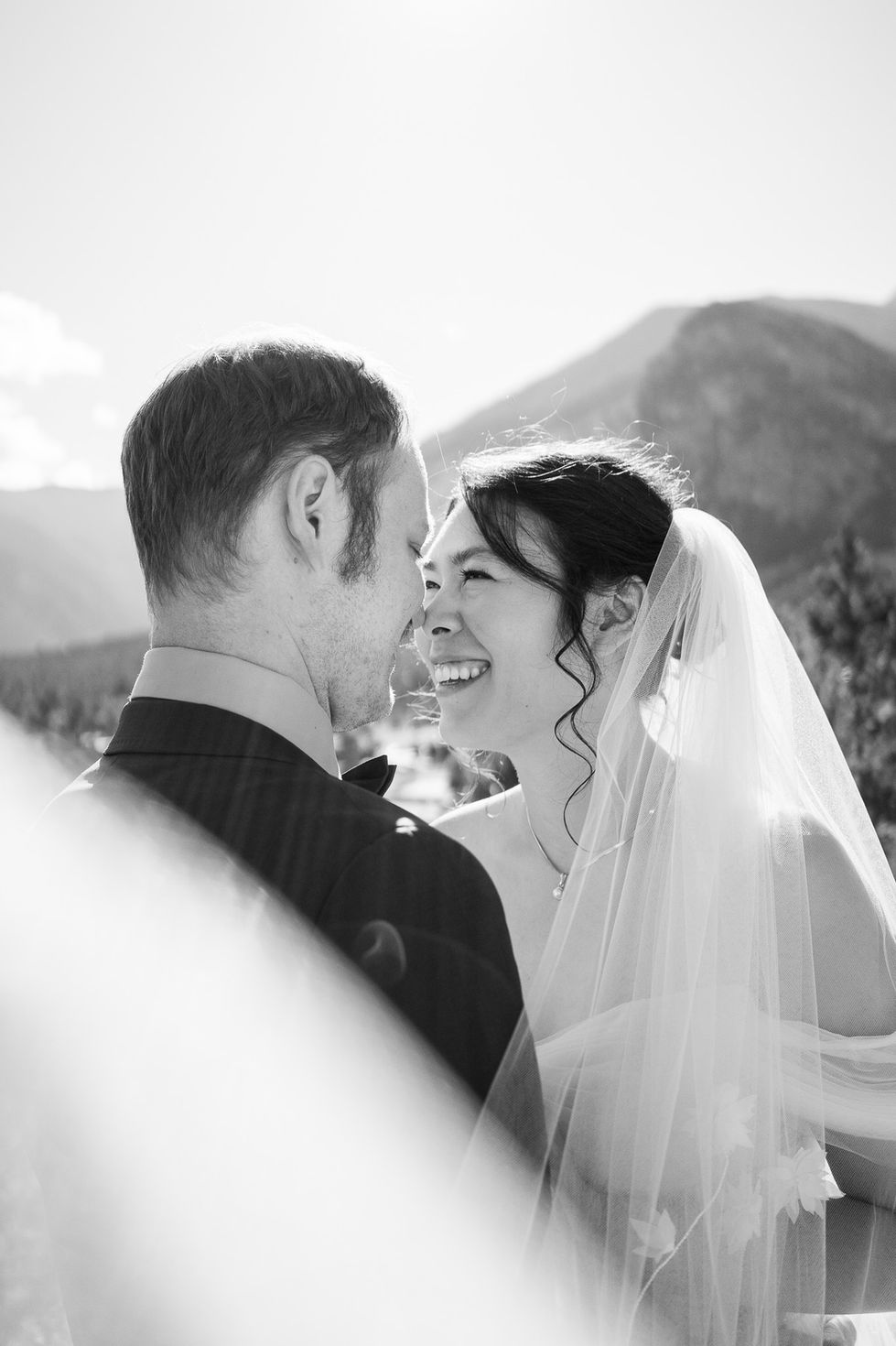 black and white bride and groom smiling at each other with mountains in background — wedding photography by Shutter & Sojourn