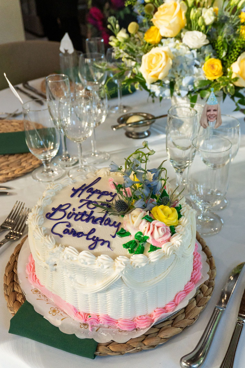 birthday cake surrounded by flowers and fancy place settings