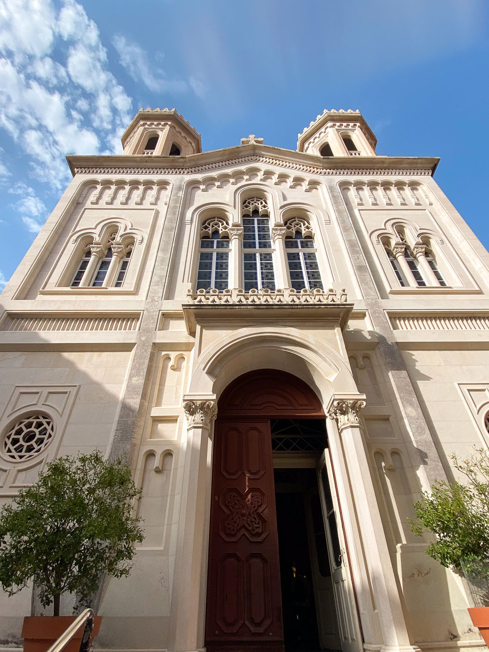 white cathedral church towering over small green trees with door open — travel photography by Shutter & Sojourn