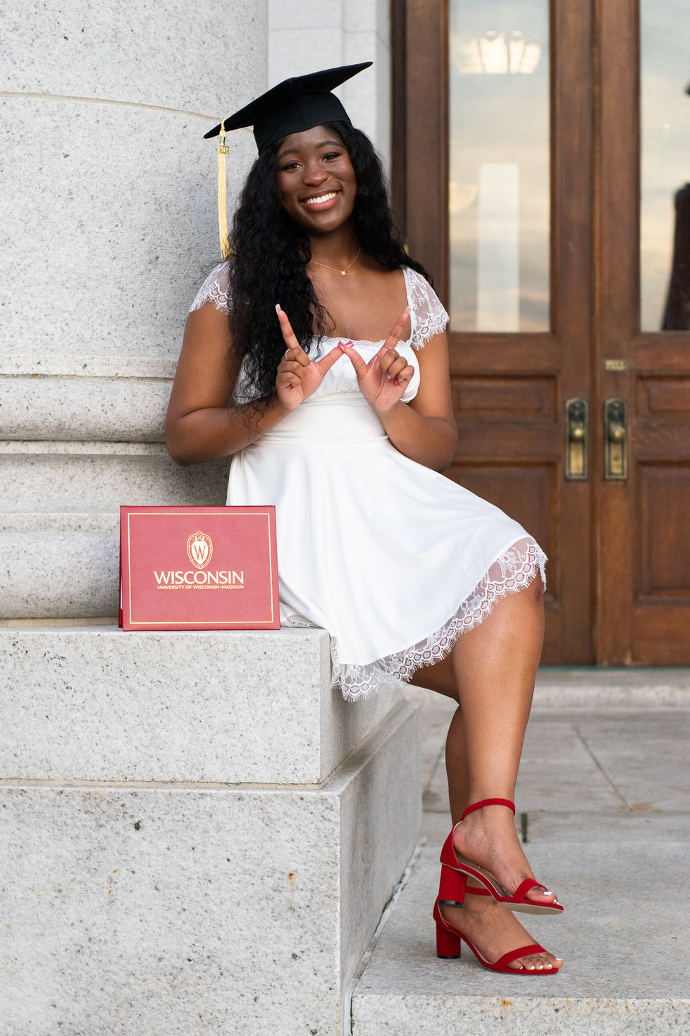 black college graduate wearing white dress and red heels at state capitol while making "w" with her hands High school senior boy looking off into the distance in green field — graduation photography by Shutter & Sojourn