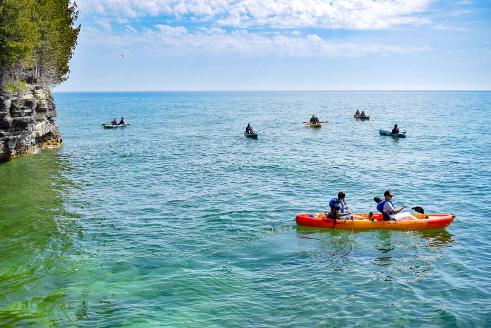 kayak tour at cave point on Lake Michigan with orange and yellow kayak in foreground — tour photography by Shutter & Sojourn