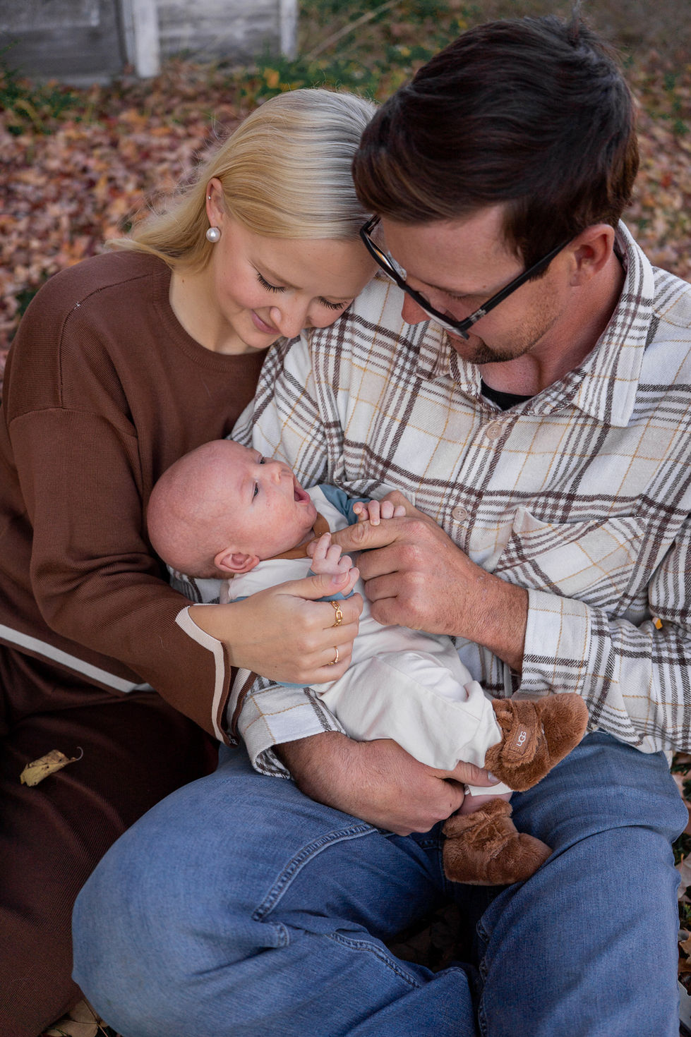 couple sitting outside looking down at their new baby — family photography by Shutter & Sojourn