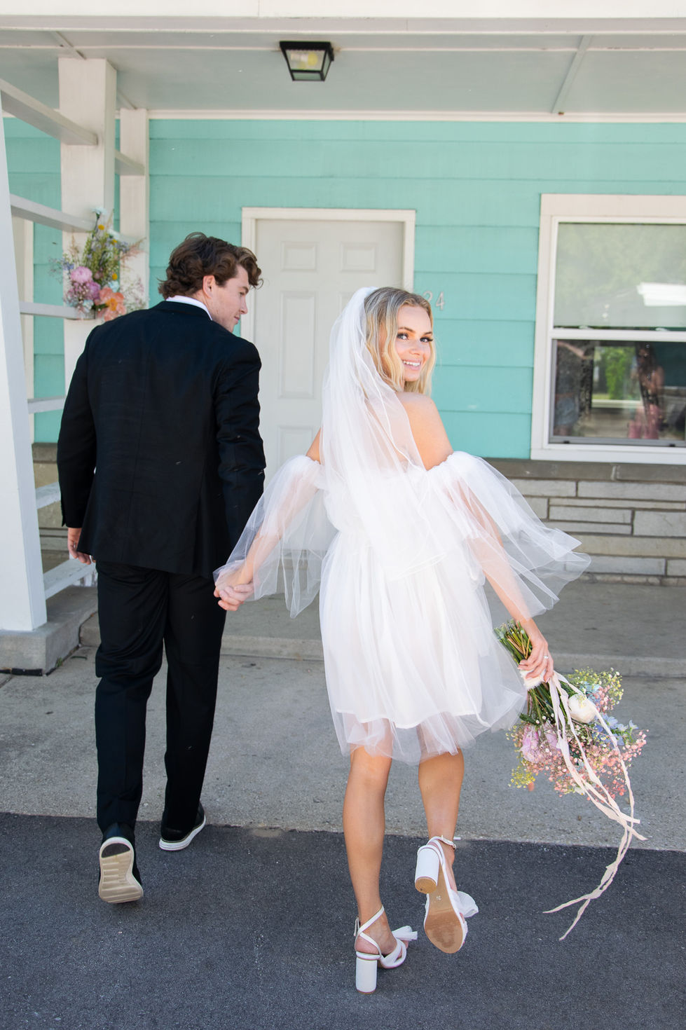 bride smiling back over her shoulder while groom leads her to hotel room after eloping — wedding photography by Shutter & Sojourn