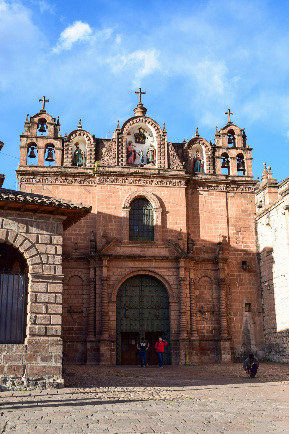 Entryway to Cusco Cathedral with shadow cutting across large green doorway — travel photography by Shutter & Sojourn
