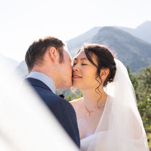 aesthetic bride and groom portrait of groom kissing bride's cheek with mountains in background — wedding photography by Shutter & Sojourn