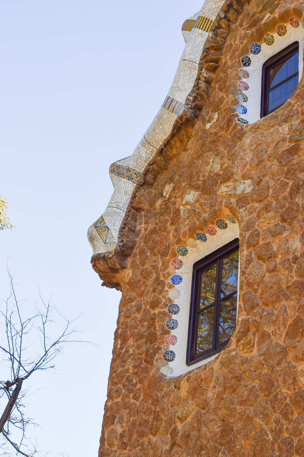 corner of Antoni gaudi designed stone building with colorful mosaic windows — travel photography by Shutter & Sojourn