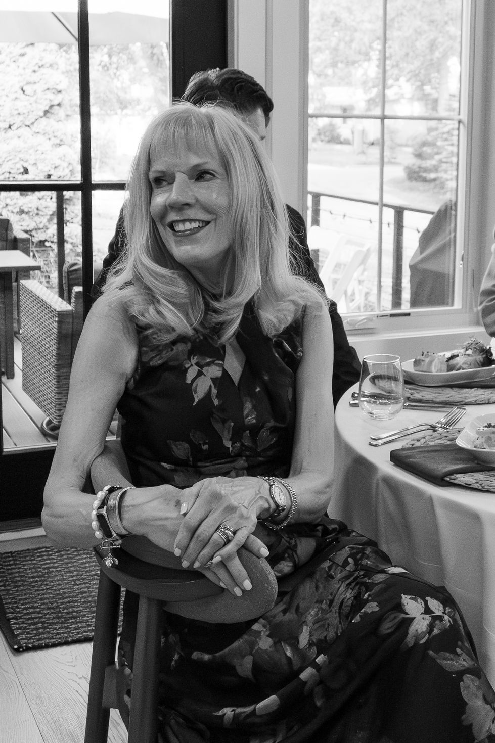 black and white older woman in dress and jewelry smiling over her shoulder