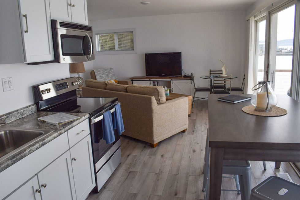 open concept small kitchen and living room with tan couch — real estate photography by Shutter & Sojourn