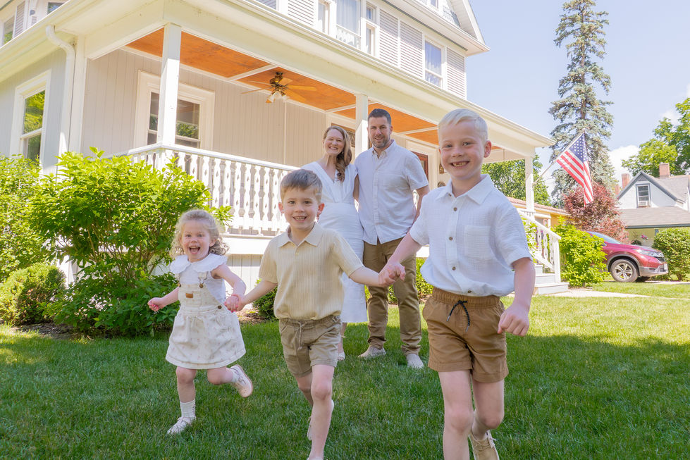 3 young kids holding hands and running while their parents hug and smile