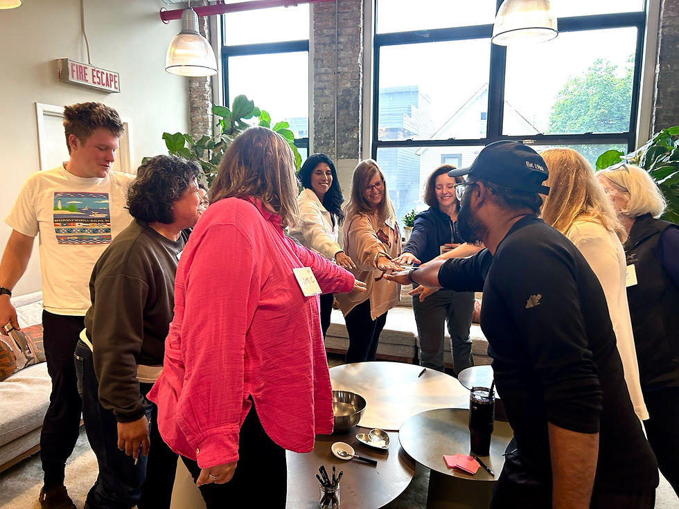 A corporate group at ALTAR putting their hands in the center of a huddle.