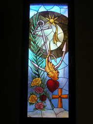 Vidriera religiosa con Sagrado Corazón y cruz en el Altar Mayor de la Iglesia Salesianas de María Auxiliadora en Sanlúcar La Mayor.