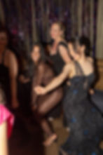 Women dancing at a celebratory event in formal attire.