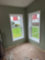Two new white-trimmed windows in a green gallery room.