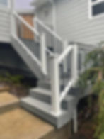 Modern grey deck stairs with white railings in a gallery.