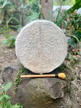 Shamanic drum with white fur, sat on a rock.