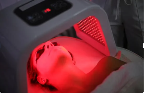 An image of a woman's face under a red light device