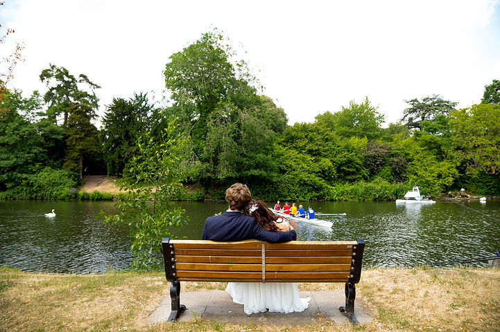 Couple sit on a park bench looking at the river Avon