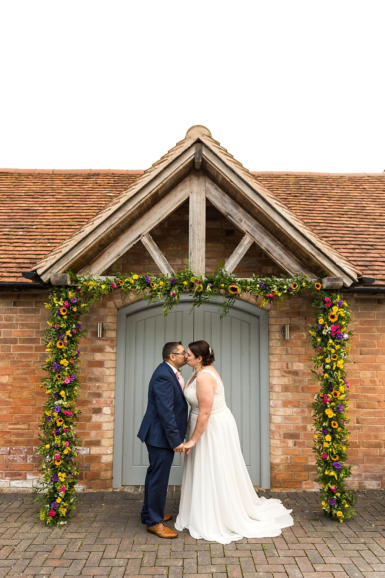 Bride and groom kiss underneath a flower arch at Swallows Nest Wedding