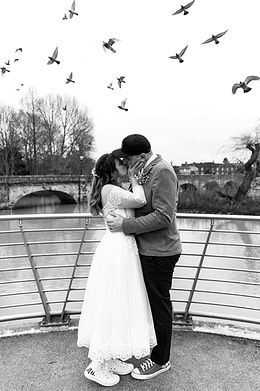 Bride and groom kiss with birds in the sky