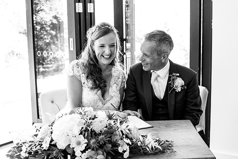 Happy couple smile while signing the wedding certificate
