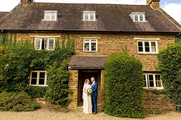 Bride and groom stand in front of Dodmoor House