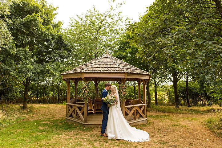 Bride and groom pose by The Orchard Pavillion at Crockwell Farm