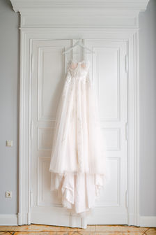 Brautkleid hängt an weißer Tür