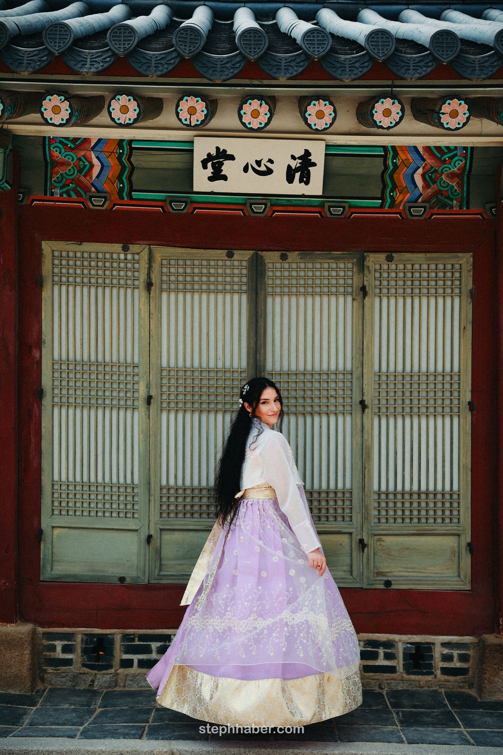 Woman in traditional attire standing before ornate building.