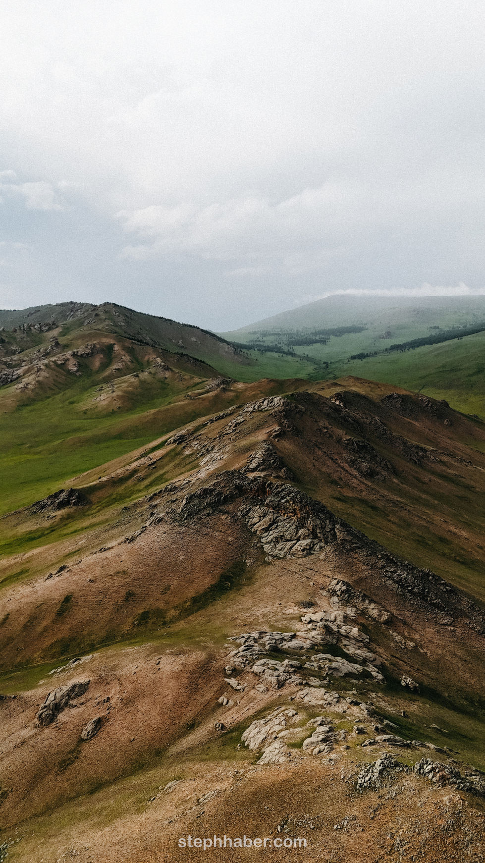 Mountainous landscape with rolling green hills and clouds.