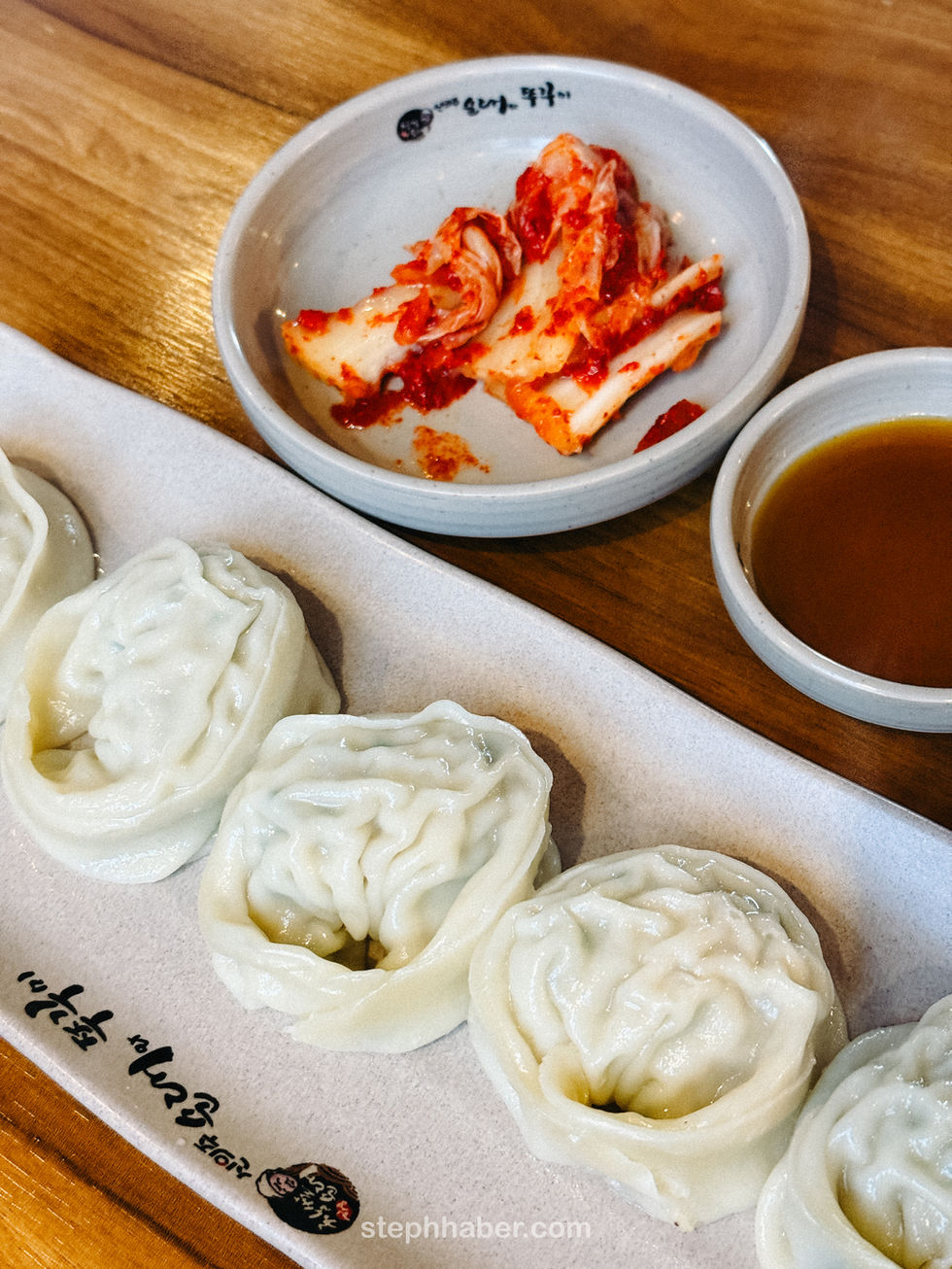 Dumplings with kimchi and dipping sauce on the side.