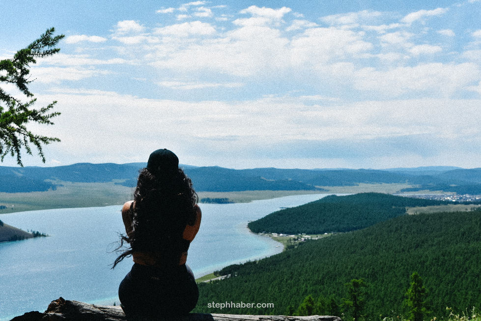 Person overlooking scenic lake and forest landscape.