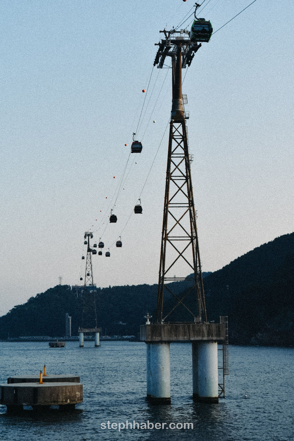 Cable cars over water with distant hills.
