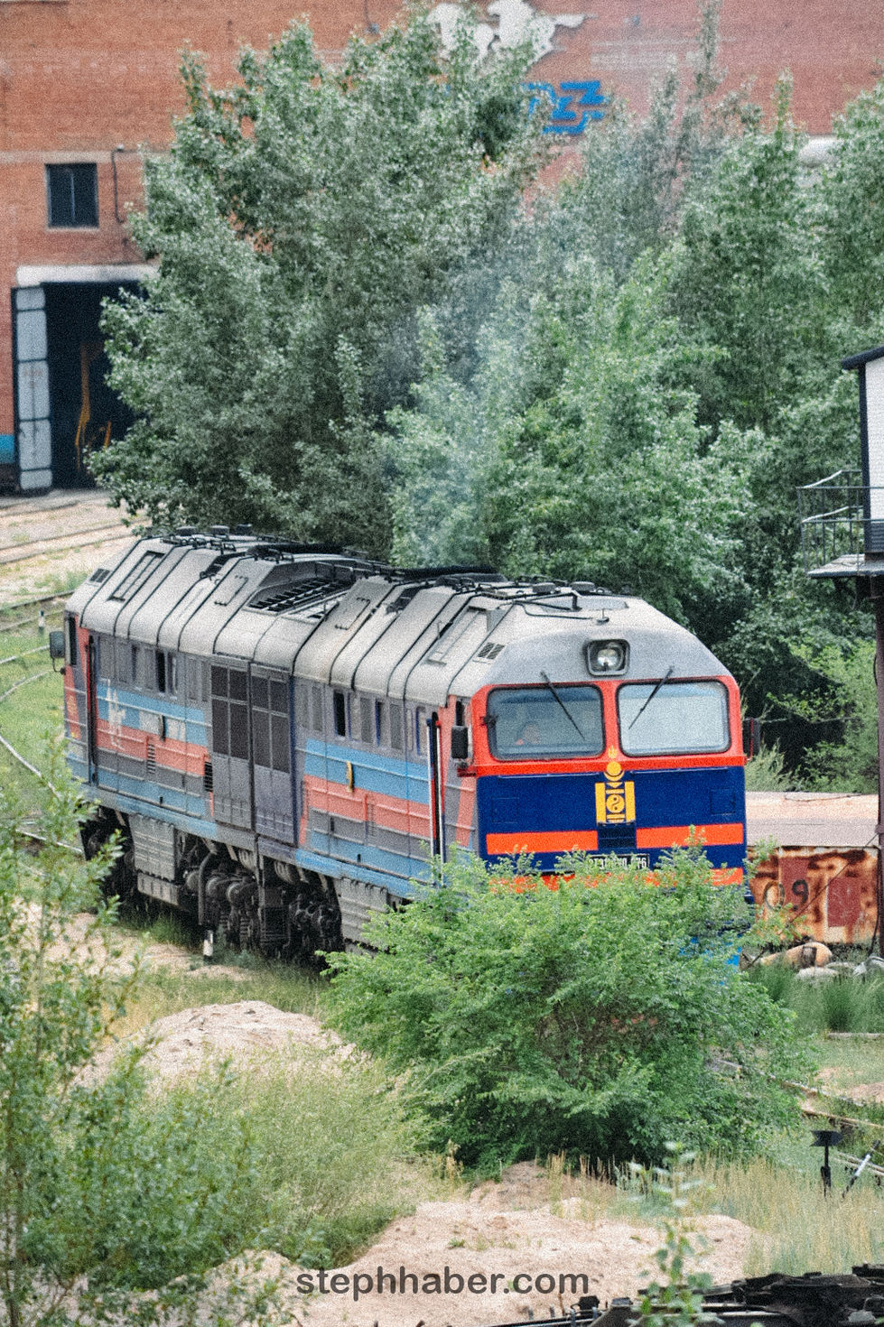 Train near trees and building, outdoors. Mongolia
